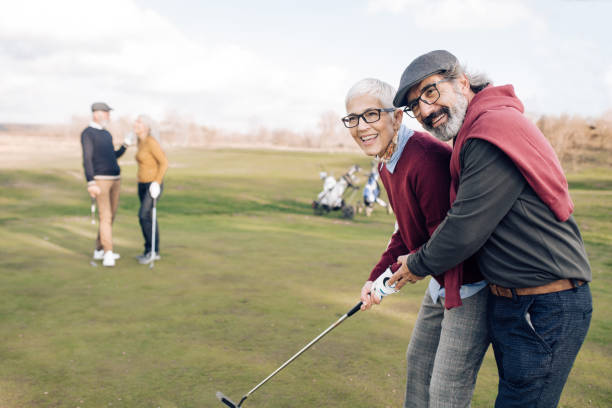 istock Senior man teaching his wife how to take a golf shot 1260814187