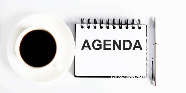 istock Business agenda, planning concept. Spiral notebook with Agenda text on white background with coffe 1260960053
