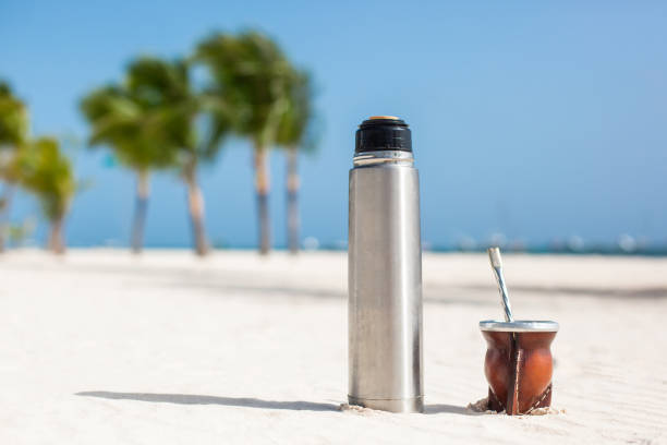 thé traditionnel latino-américain de mate et un thermos d’eau chaude sur une plage tropicale - tea island photos et images de collection