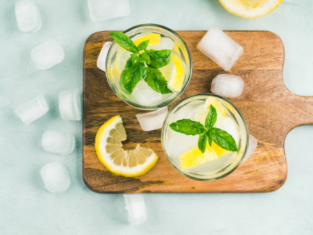 Fresh lemon lemonade in jug and glasses Fresh lemonade in jug and glasses with ice, mint leaves and lemon slices on bright gray and blue background. Top view vodka soda top view stock pictures, royalty-free photos & images