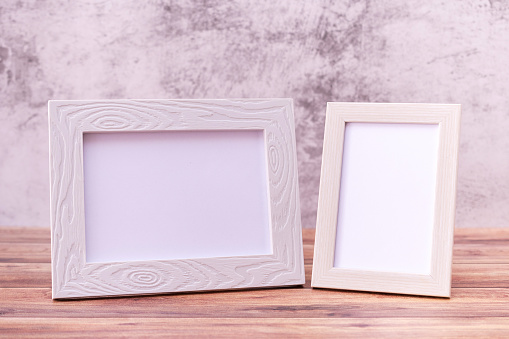 Two Picture frame on wall background and wooden table. Poster product design styled