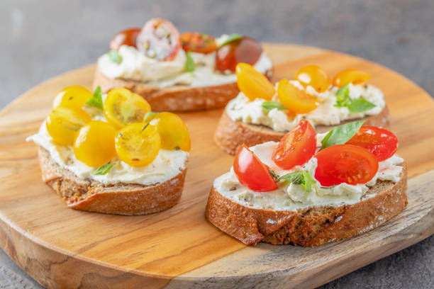 istock Delicious crusty bread slices with cream cheese and different tomato cherry  garnished with fresh basil leaves on the table .Appetizer bruschetta or snack 1261099796