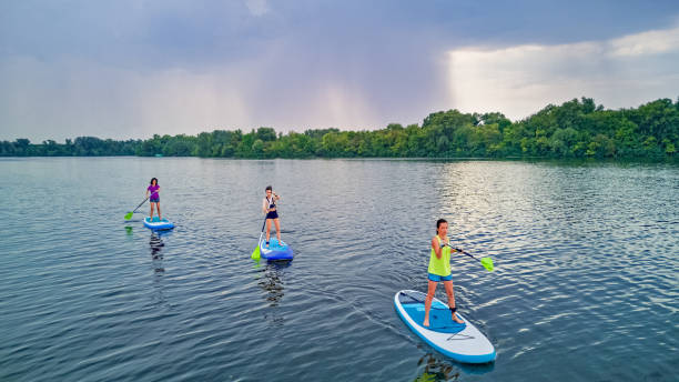 aktive familie auf sups, aufstehen paddleboards, im flusswasser, sommer familiensport, luft-top-ansicht von oben - paddelbrett stock-fotos und bilder