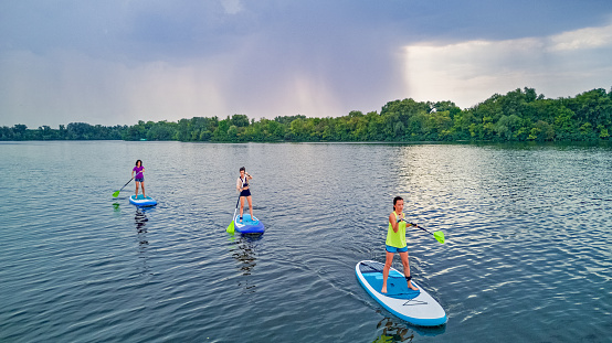 Active family on SUPs, standing up paddleboards, in river water, summer family sport, aerial top view from above