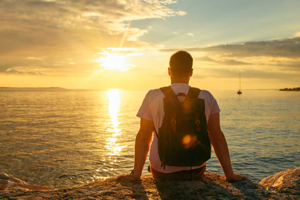istock man with backpack enjoying sunset over the sea 1261131262