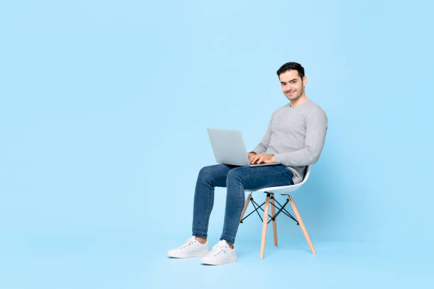 istock Smiling handsome man sitting on a chair working on laptop computer 1261136539