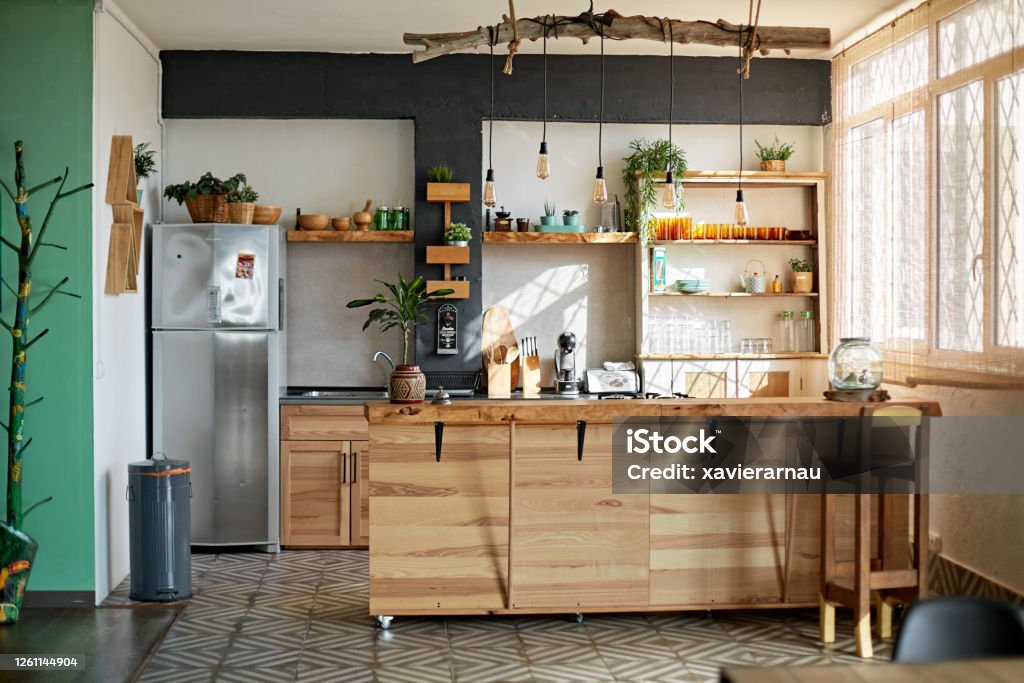 Apartment Kitchen in Modern Rustic Style Wide angle view of unoccupied modern kitchen with rustic style including wooden kitchen island and hanging pendant lighting. Kitchen Stock Photo