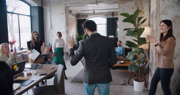 istock Camera follows successful young male boss entering office celebrated by clapping multiethnic colleagues slow motion. 1261144925