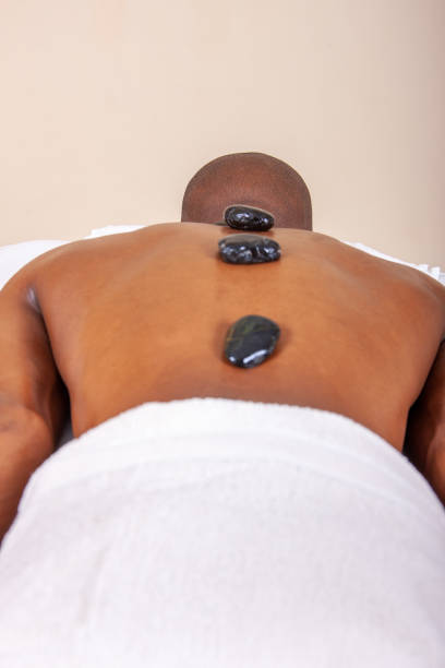 african young man getting a hot stone thai massage in a spa bed