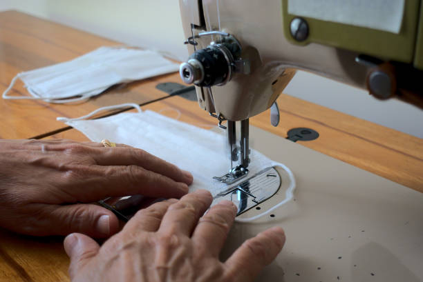 istock Close up shot woman manufacturing surgical mask using a sewing machine 1261164747