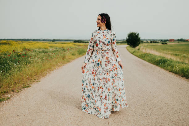 mujer con un vestido caminando en un día soleado en la naturaleza - floral dress fotografías e imágenes de stock