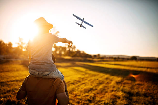 Let's fly Father caring kid on shoulders in nature toy airplane stock pictures, royalty-free photos & images