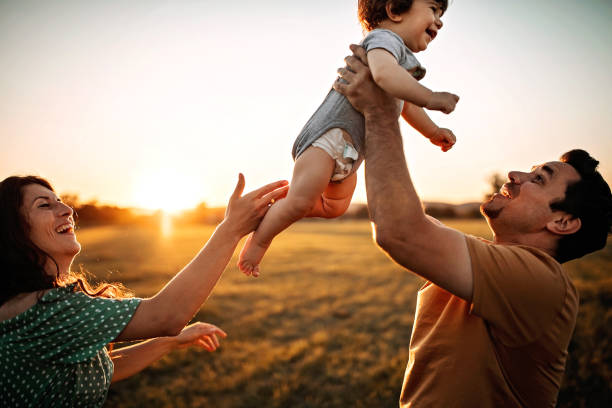istock Parents playing with kid in meadow 1261272744