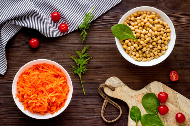 Vegetarian meal. Chickpeas and carrot in bowls on dark wooden table top view
