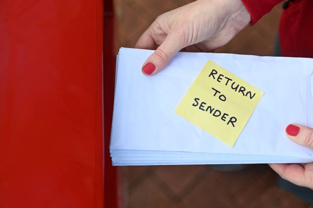 istock Woman sending return to sander letters in envelope in red mail box 1261290506