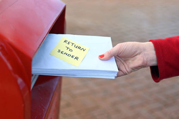 istock Woman sending return to sander letters in envelope in red mail box 1261290524