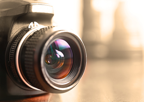 Close up of camera lens and photography equipment on a wooden table.