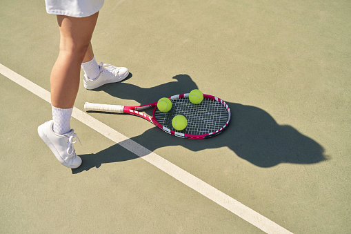 Close-up shot of tennis ball and racket, Female feet close-up on racket and ball tennis court.