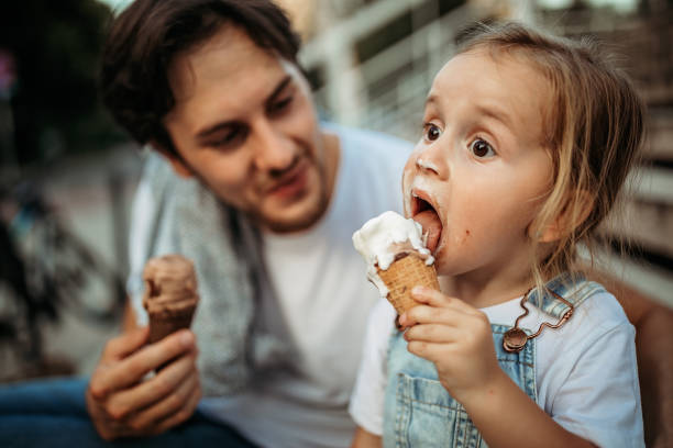 Messy girl Father and daughter licking ice cream in public park licking ice cream cone stock pictures, royalty-free photos & images