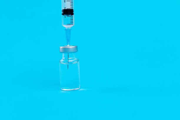 istock Syringe inserted into the vial on blue background 1261359594