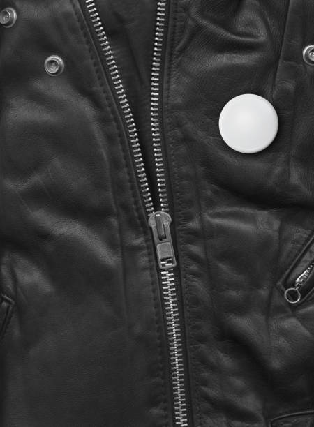 Leather jackets and denim jackets on a metal wall hanger. Women's clothes hanging on a wall hanger. Hooks with clothes hangers on a wall.