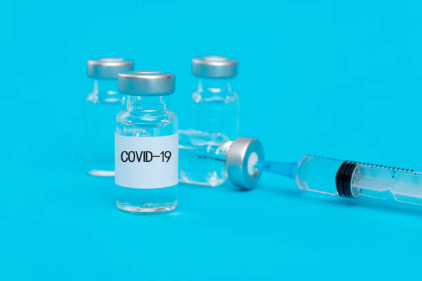 istock Syringe and Covid-19 vaccine vials on blue background 1261372789