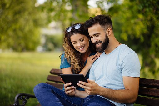 Young couple with digital tablet surfing the net in the park