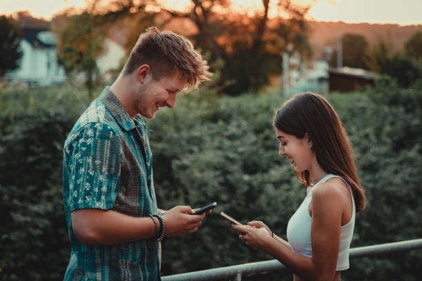 jeunes couples ayant l’amusement ensemble lisant des messages sur le téléphone portable - humor men laughing teenager photos et images de collection