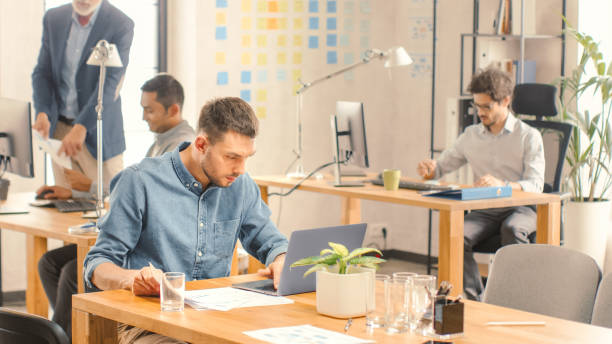 istock Modern Startup Chief Analyst Works on a Computer under Firm Strategy, Analyzes Data and Information. Modern Office of a new Company with Diverse People. 1261396915