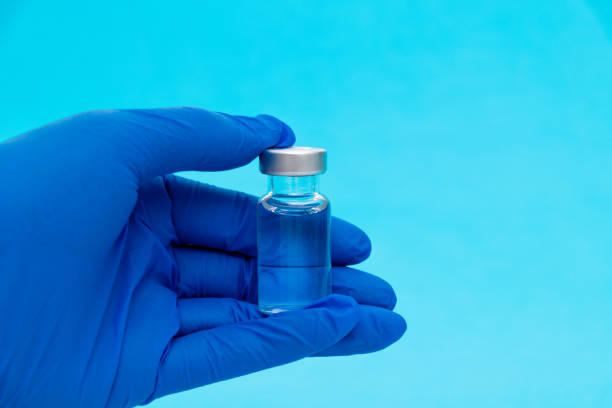 istock Hand holding a medical ampoule on blue background 1261420256
