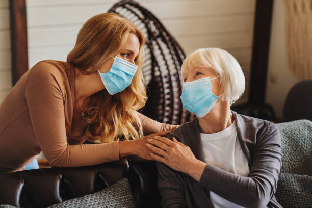 senior woman with caring daughter at home. females wearing medical masks. - mother enjoyment built structure human head imagens e fotografias de stock