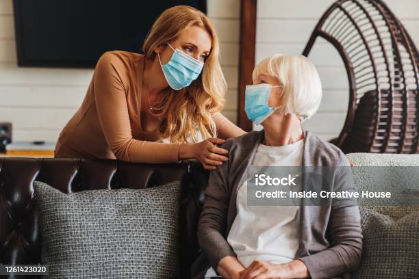 Seniorin In Medizinischer Maske Mit Sozialarbeiterin Zu Besuch Zu Hause Stockfoto und mehr Bilder von Schutzmaske