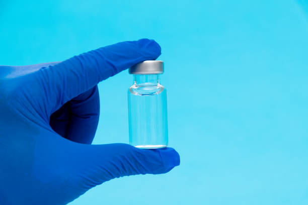 istock Hand holding a medical ampoule on blue background 1261423056