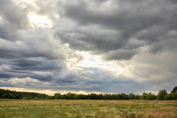 istock Cloudy field with sunshine breaking through the cloud cover 1261424702