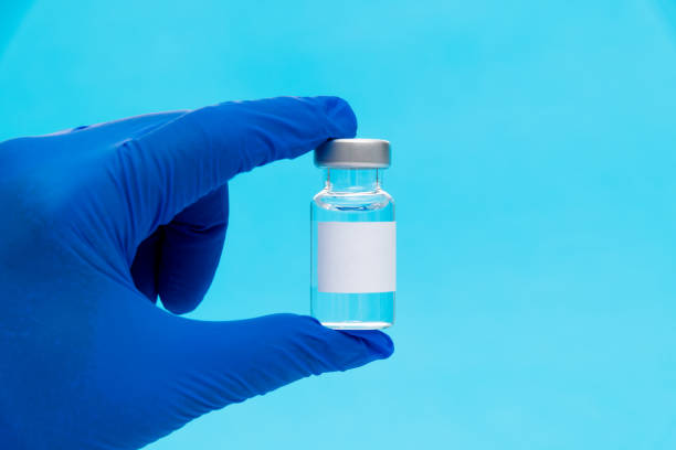 istock Hand holding a medical ampoule on blue background 1261426356