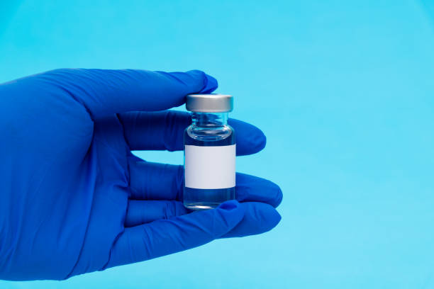 istock Hand holding a medical ampoule on blue background 1261428060