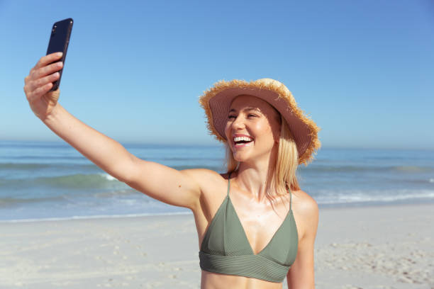 istock Woman smiling while taking a selfie on the beach 1261466397