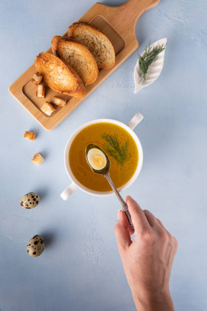 istock Putting half of quail egg in bouillon in bowl 1261468505