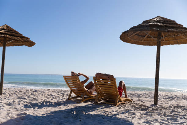 istock Caucasian couple sitting on deck chairs at the beach 1261483334