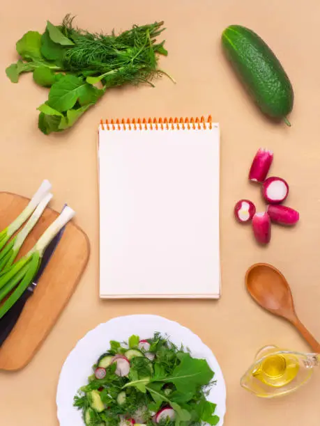 Photo of The concept of a healthy vegan diet. A clean notebook with fresh vegetables and herbs. The Concept Of Vegetarian Cooking