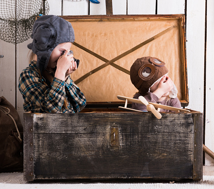 two little girls in hats playing in big wooden chest with old camera