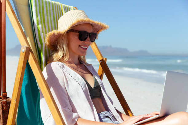 istock Woman using laptop at the beach 1261543115
