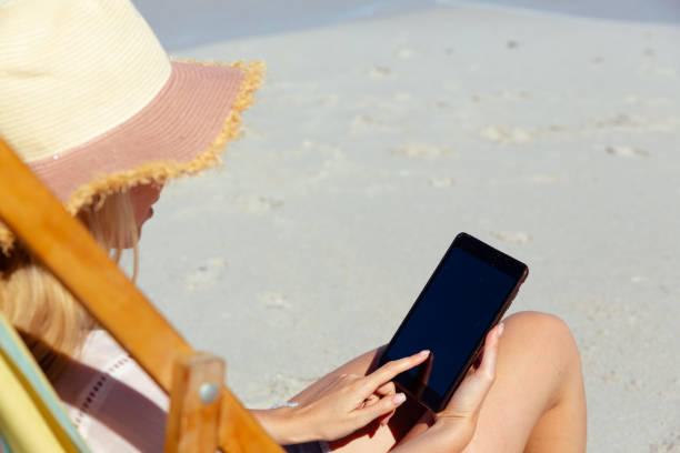 istock Rear view of woman using smartphone at the beach 1261543657