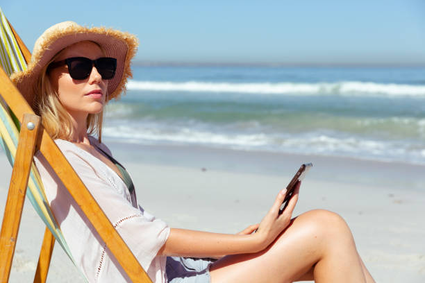 istock Woman using smartphone at the beach 1261544818