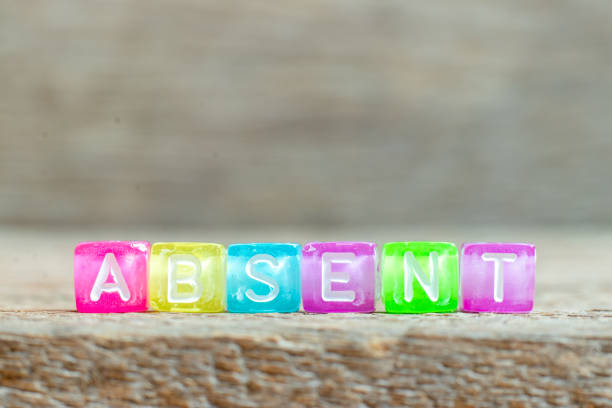 istock Clear bead with white letter in word absent on wood background 1261554553