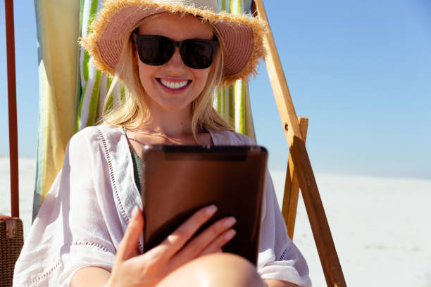 istock Woman using digital tablet at the beach 1261557297