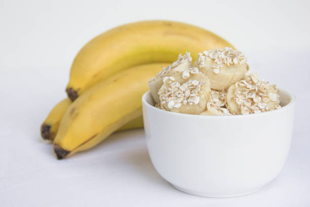 A bunch of bananas and a sliced banana with oats in a jar on the table. stock photo