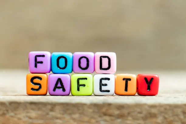 Photo of Colorful bead with black letter in word food safety on wood background