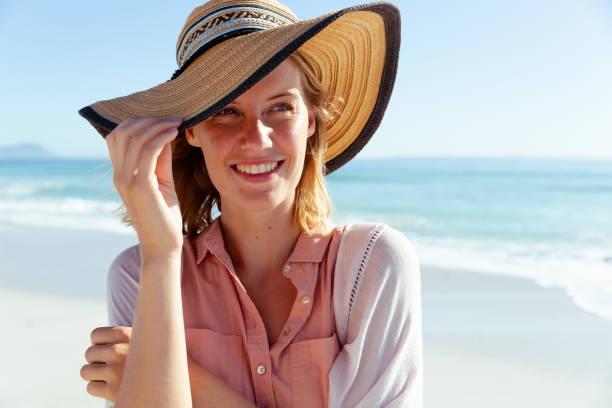 istock Woman wearing hat smiling on the beach 1261563649