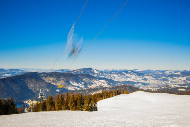 Mesmerizing funicular road located in a picturesque place among mountains and snowy hills and on frosty winter evening on blue sky. Concept of winter tourism in European countries. Advertising space